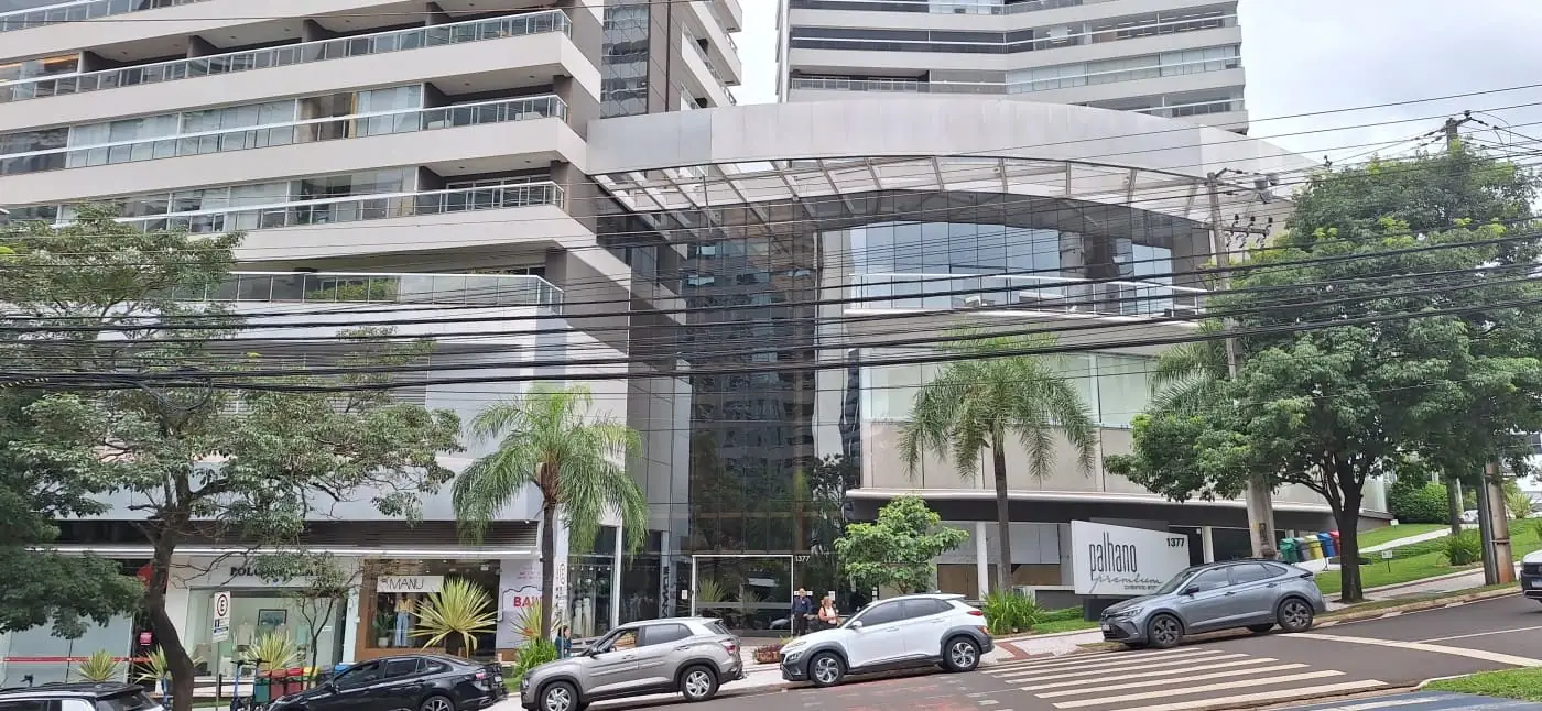 Fachada do edifício Palhano Premium, com entrada envidraçada e palmeiras